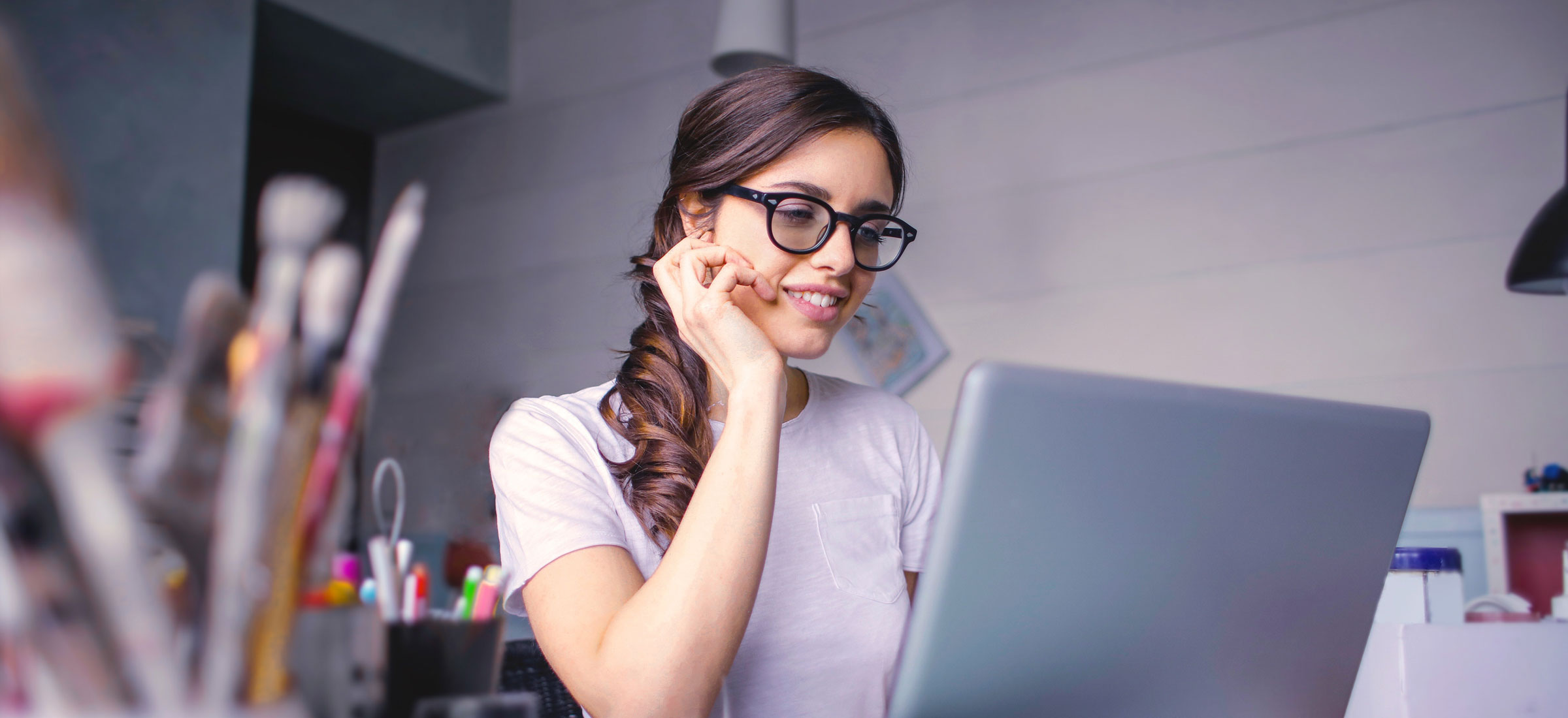 Eine Frau sitzt vor einem Laptop und lächelt